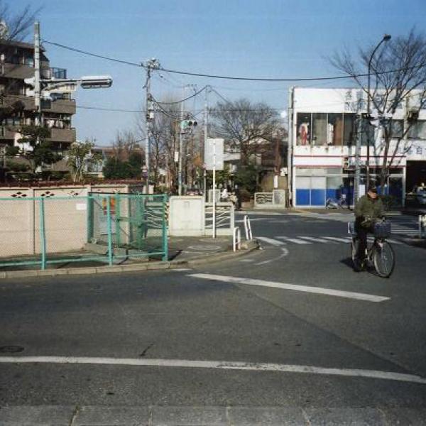現在の水道端停留所付近：　 コンクリ－トの塀と手前のフェンスの間に千川が流れている。青梅街道の向う側の信号の右に暗渠となった千川の遊歩道が続いている。