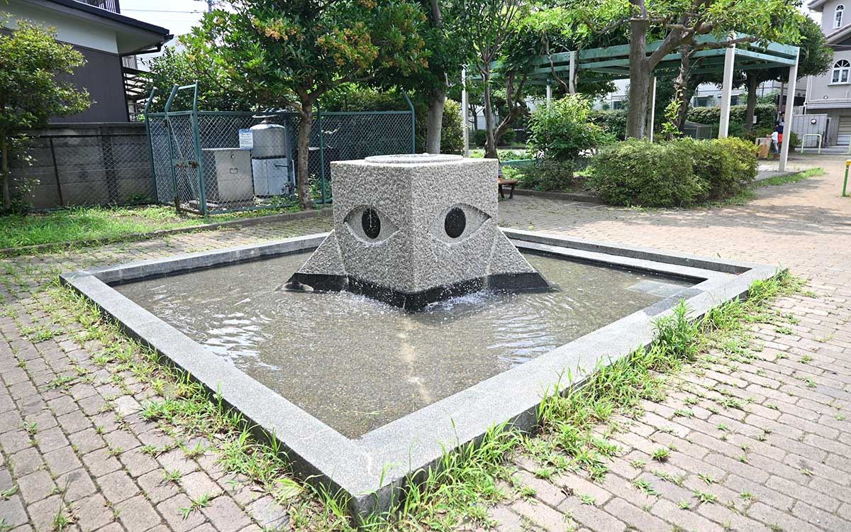 中央にユニークなオブジェが置かれた四角いじゃぶじゃぶ池がある